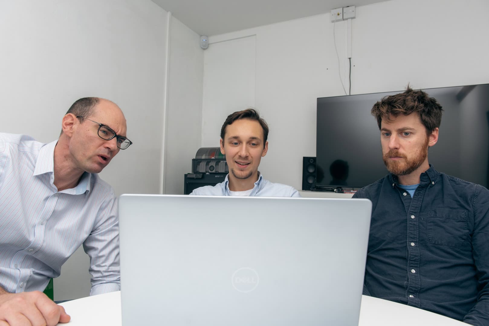 web development team meeting around a laptop