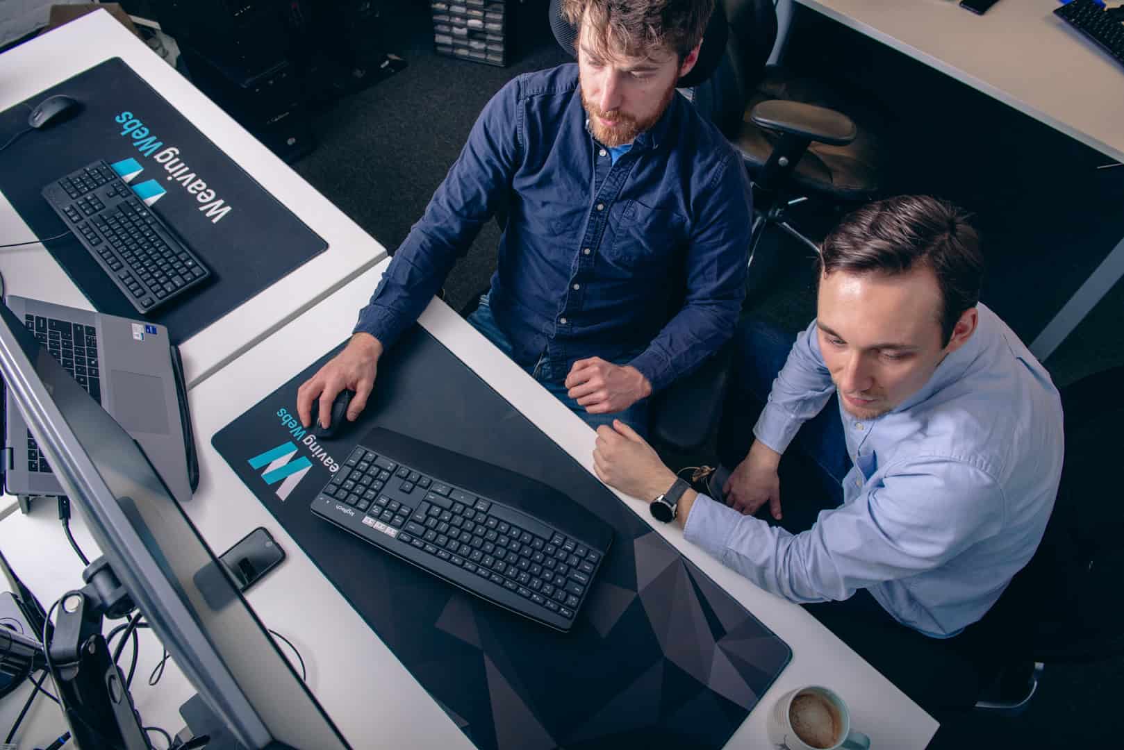 Two guys sat working collaboratively in the Weaving Webs office